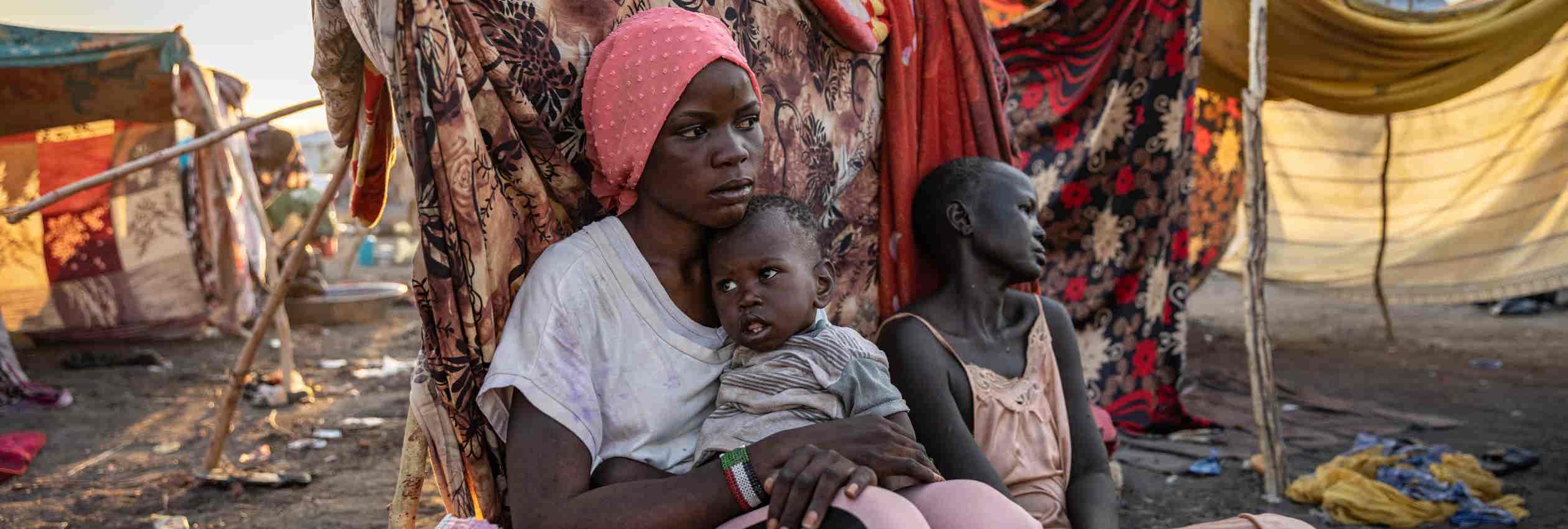 Nyauke, 18, sits with her mother and baby sister at a UNHCR transit centre near the South Sudanese border after fleeing violence in Bentiu, Sudan.
