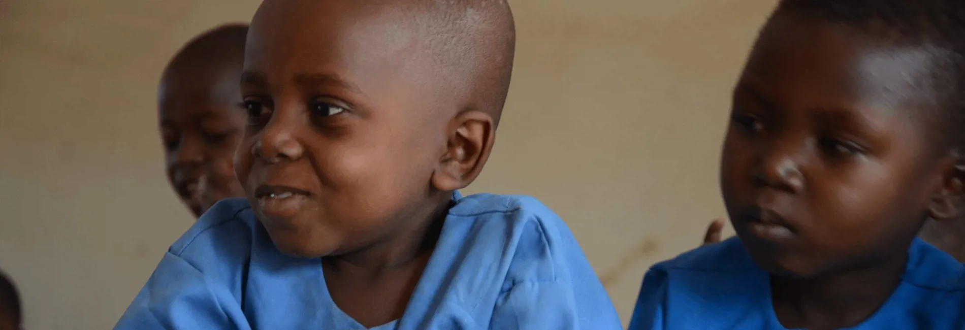 Azaiya, a six-year-old boy from Cameroon, sits with classmates during a lesson