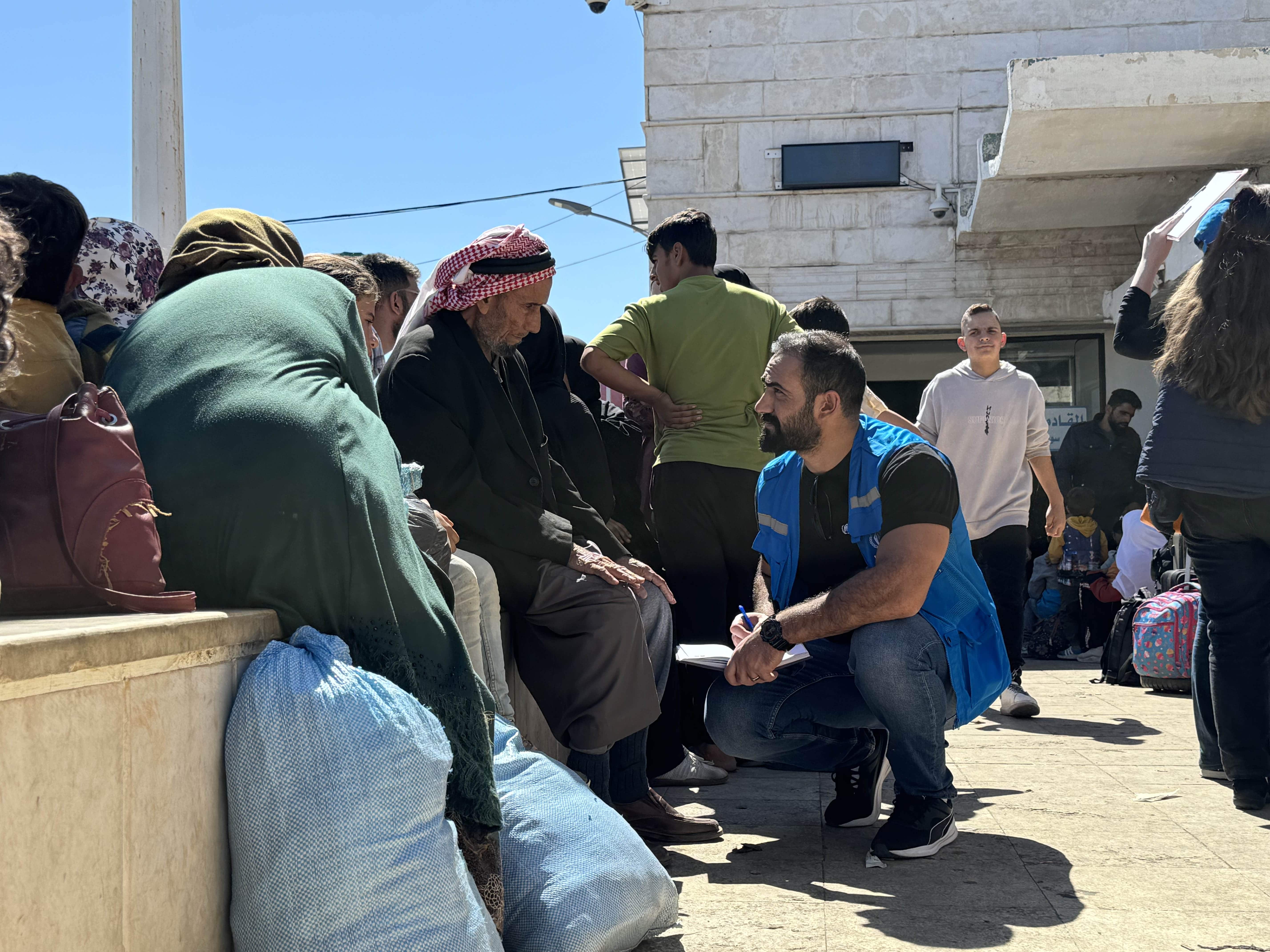 A UNHCR staff member talks to families arriving from Lebanon at the Jdaidet Yabous border crossing in Syria.