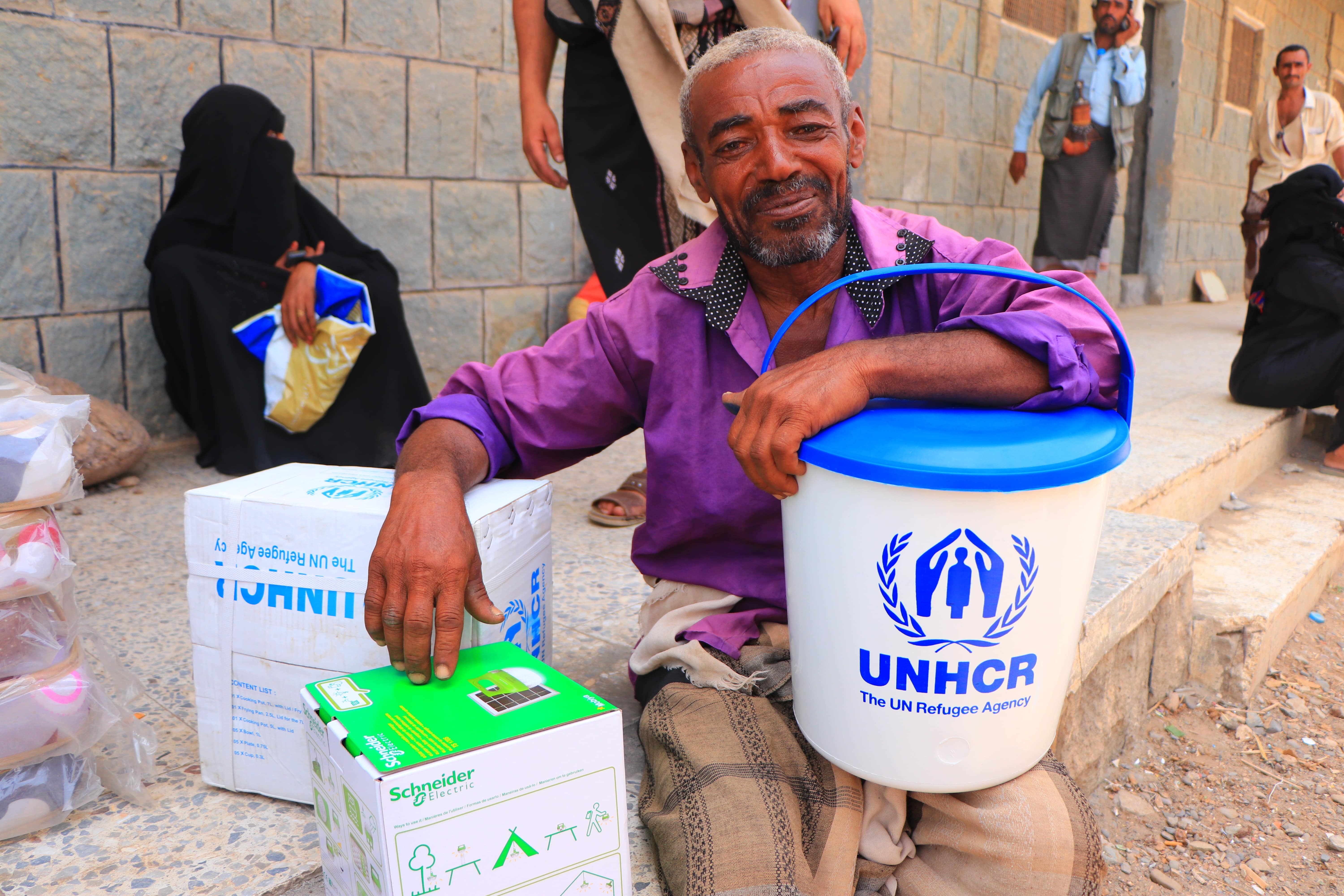 Man with UNHCR supplies looks at camera. Displaced families in Yemen receive essential household items.