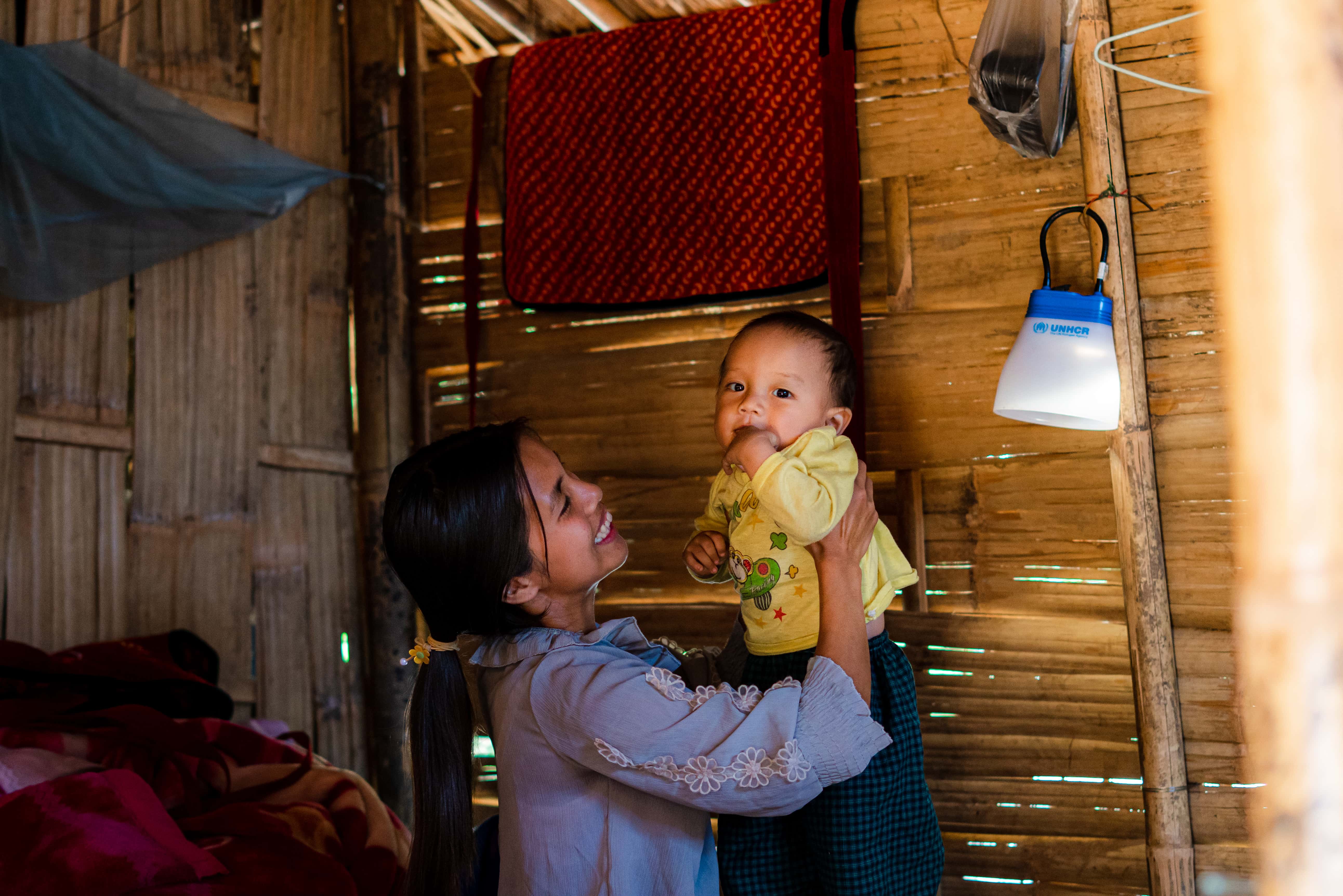 A displaced woman plays with her baby in their shelter. Myanmar faces overlapping crises, with around 3.5 million people displaced inside the country.