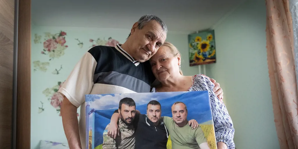 Mariia and Anatolii, who were displaced by the war in Ukraine, hold a picture of their three sons