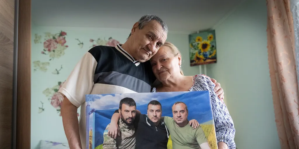 Mariia and Anatolii, who were displaced by the war in Ukraine, hold a picture of their three sons