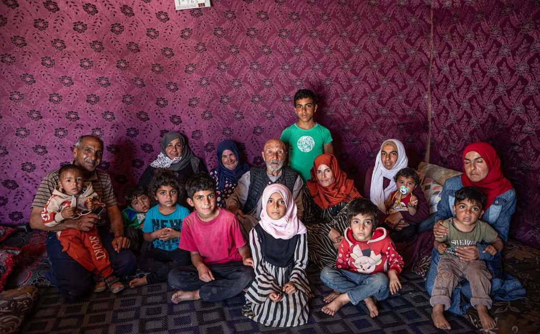 Jassim and several generations of his family sit in the tent they built on the site of their destroyed home.