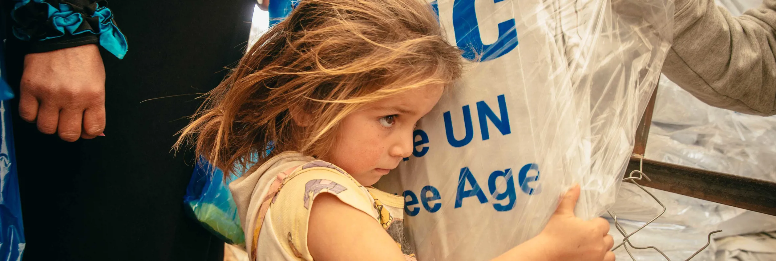 Syrian refugees receive plastic sheets at a distribution center in Jordan’s Zaatari refugee camp.
