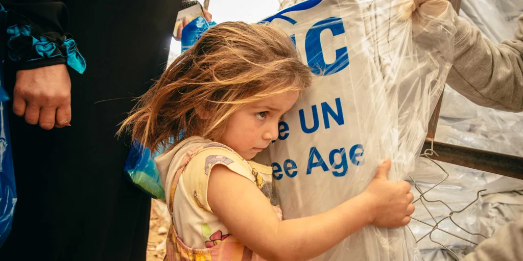 Syrian refugees receive plastic sheets at a distribution center in Jordan’s Zaatari refugee camp.