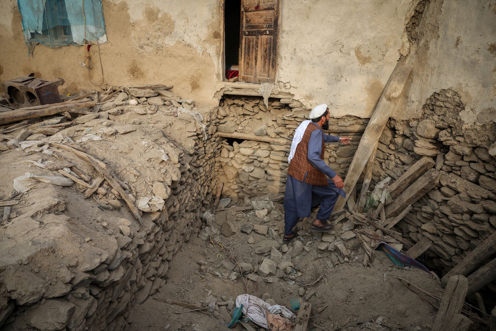 An Afghan man looks for his belongings amidst the rubble of a collapsed house after a deadly magnitude-6 earthquake that struck Afghanistan around midnight, in Dara Noor, in Jalalabad, Afghanistan