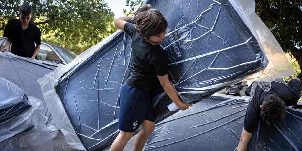 Displaced children carry UNHCR mattresses outside a hospital in Beirut Lebanon