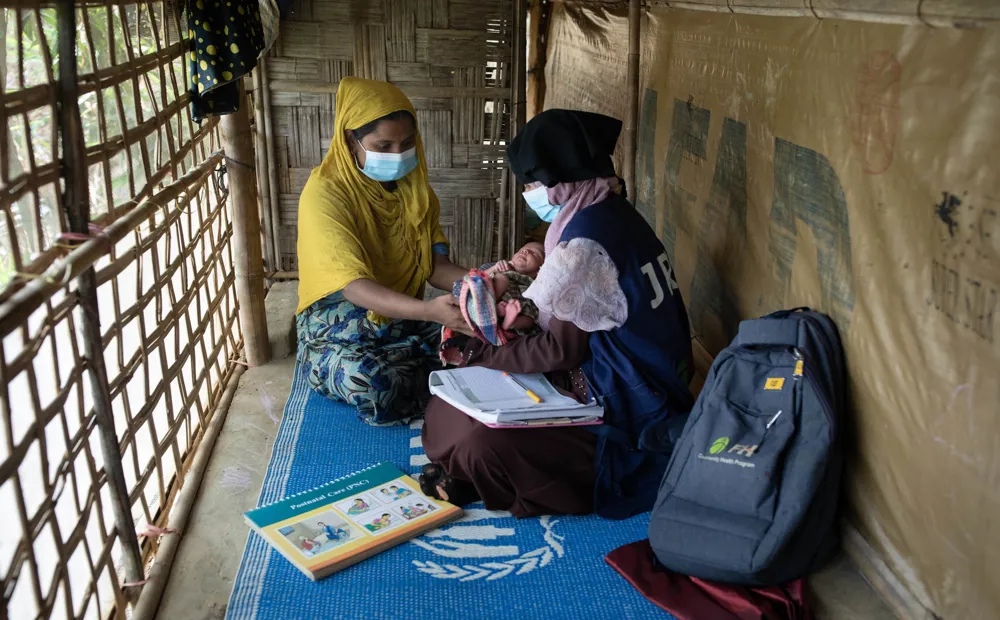A community health volunteer helps Rohingya mothers with post natal care in Bangladesh.