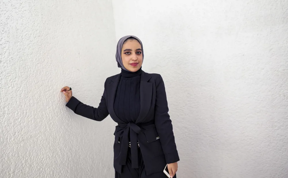 Young woman leans against wall. Fatima, from Yemen is a third-year student of Medicine at Cairo University, on a DAFI scholarship.