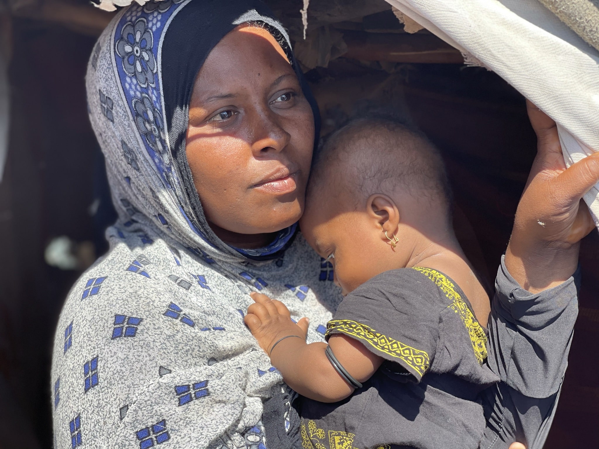 Internally displaced Yemeni mother, Lubna, holds her child after fleeing escalating fighting.