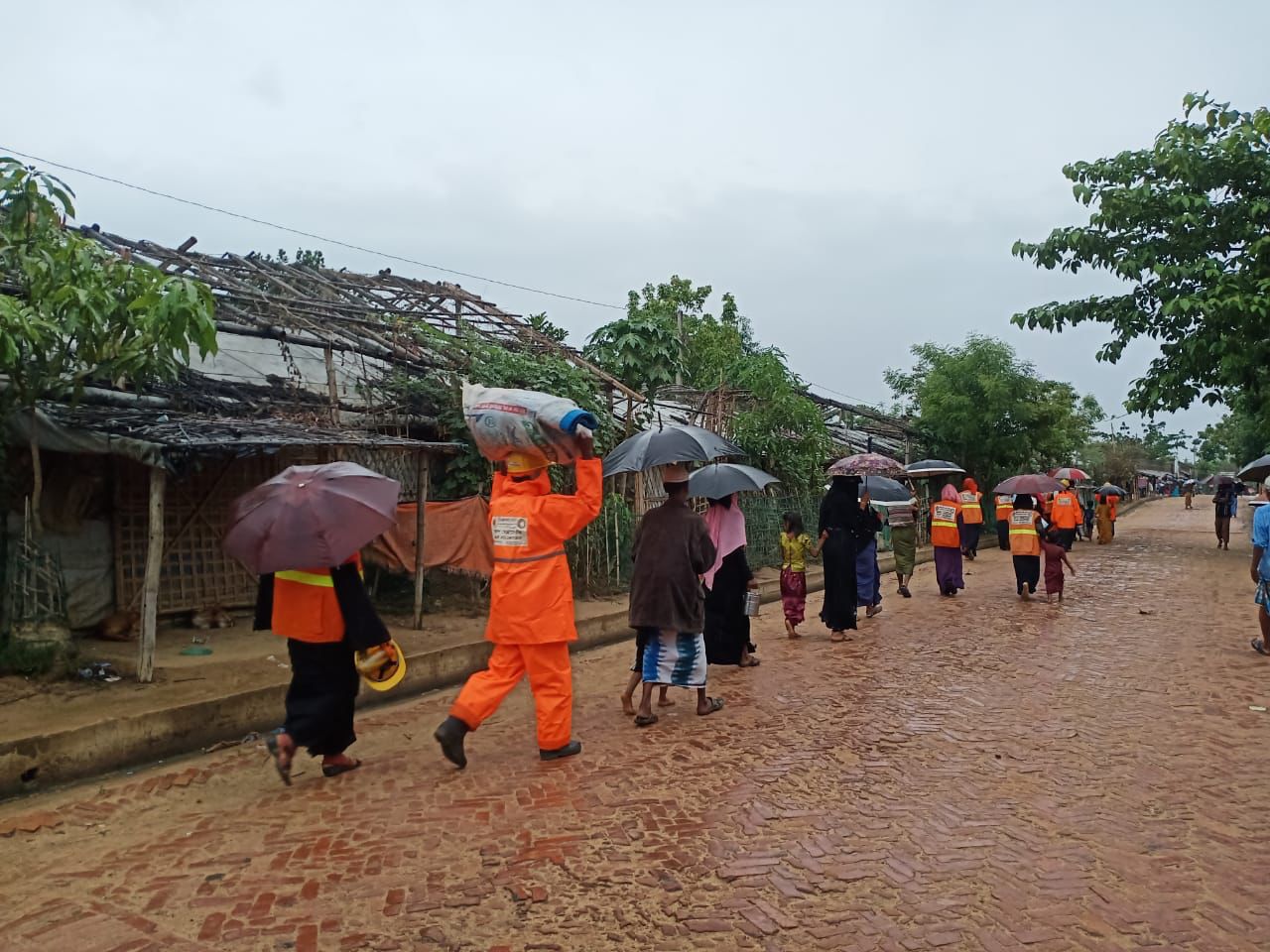 Volunteers help Rohingya refugees evacuate from their shelters as the rain falls