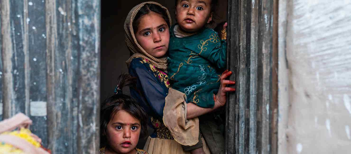 Children look out from the doorway of a new sustainable home, built with UNHCR support, in Nangarhar province, Afghanistan.