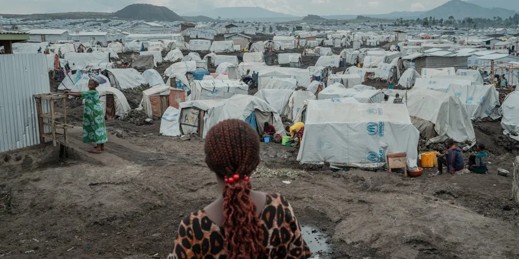 A woman looks out over tents at a crowded displacement site in eastern DRC. Overcrowding and lack of adequate hygiene and sanitation makes displaced people more vulnerable to the spread of diseases like Ebola.