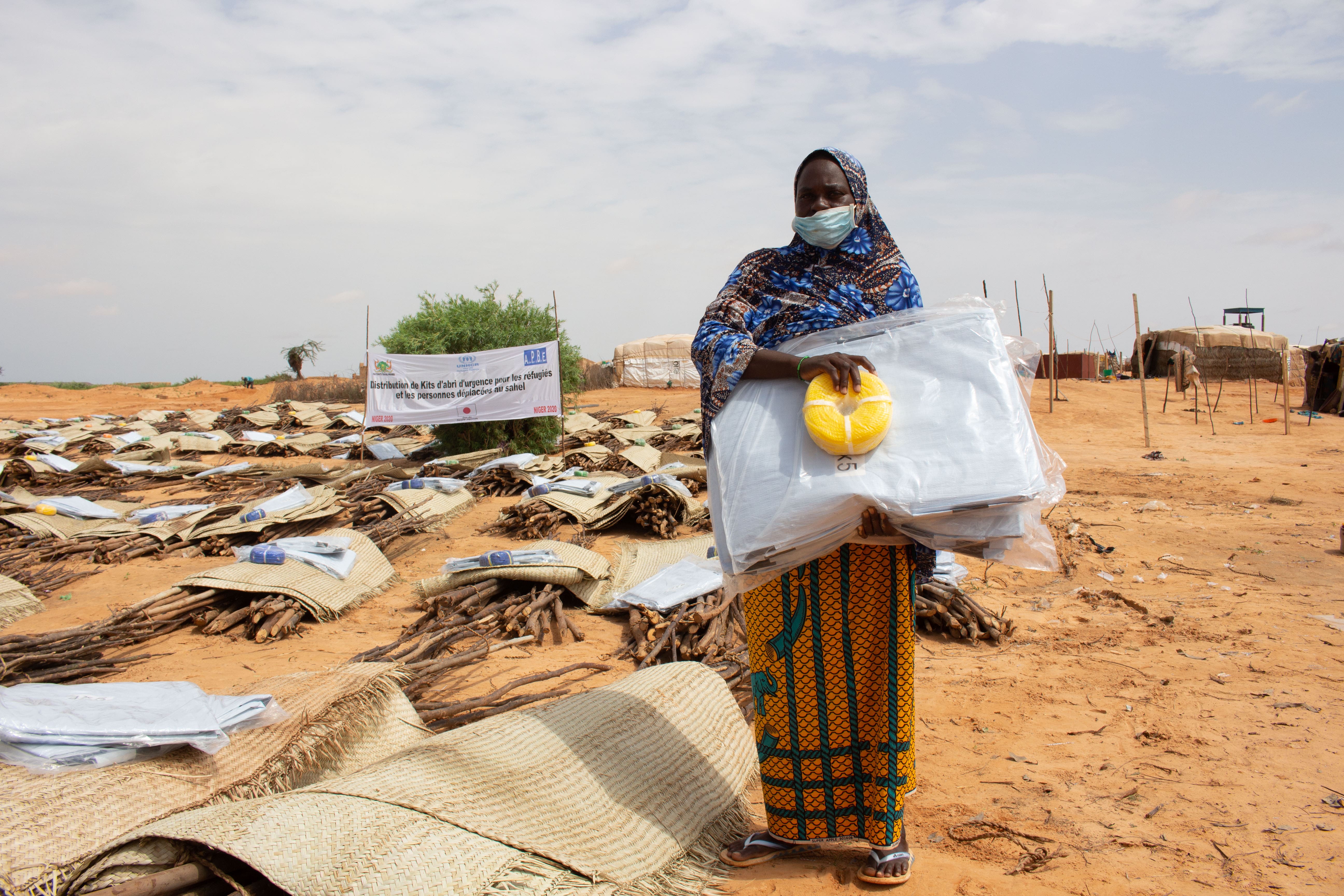 Woman standing with shelter kit. UNHCR emergency shelter kits help displaced persons in Niger.