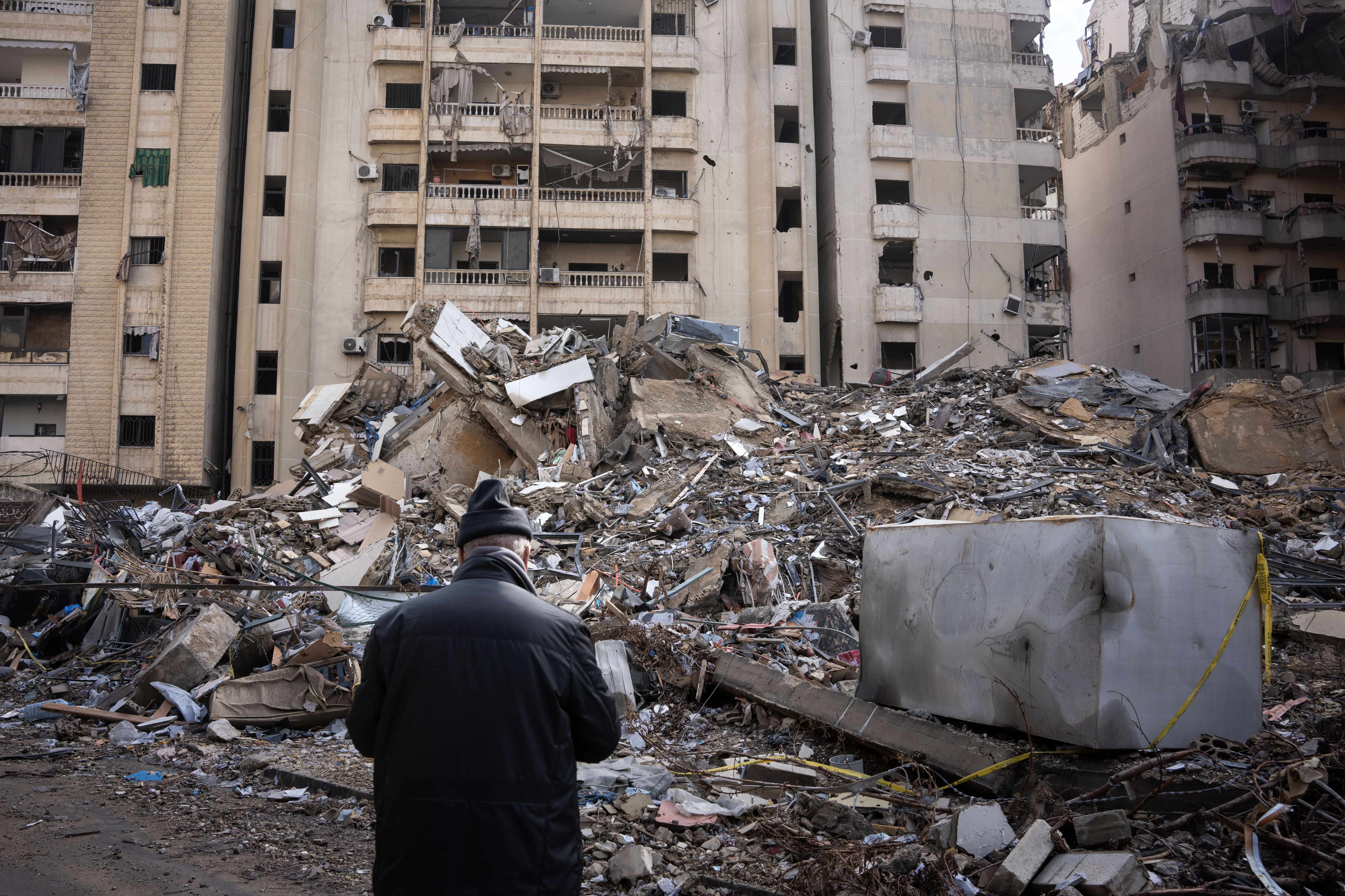 A man looks at the ruins of a bombed building during the return of civilians to Dahiye after the ceasefire